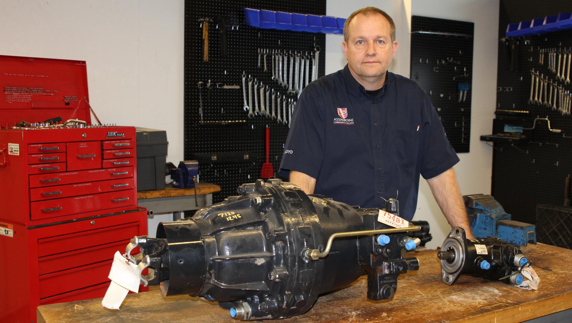Lloyd Carey stands in his classroom, beside one of his donated items - a Case IH Combine CVT drive unit 